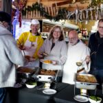 Gäste der Armenküche genießen festliches Mittagessen in der Füchschen Alm