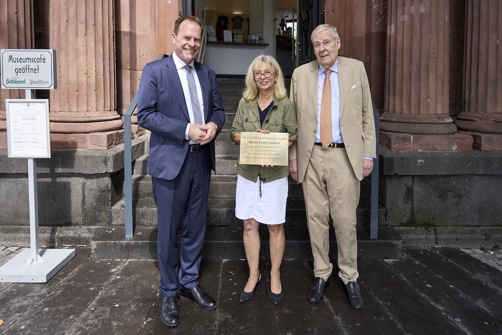 Oberbürgermeister Dr. Stephan Keller (l.) und Dr. Annette Fimpeler, Leiterin des SchifffahrtMuseums, haben am Dienstag, 29. Juli 2025, das langjährige und außerordentliche Engagement von Ernst Lamers gewürdigt. Eine Plakette am Eingang des SchifffahrtMuseums weist ab sofort auf die wertvolle Arbeit des langjährigen Förderers des Museums hin. © Landeshauptstadt Düsseldorf/Claus Langer