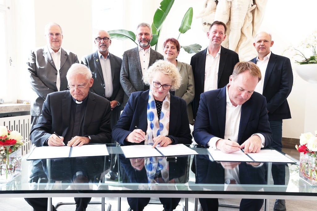 Stadtdechant Frank Heidkamp (v.l.), Marion Warden, Vorsitzende des Vorstands der liga wohlfahrt, und Oberbürgermeister Dr. Stephan Keller bei der Vertragsunterzeichnung. © Landeshauptstadt Düsseldorf/David Young