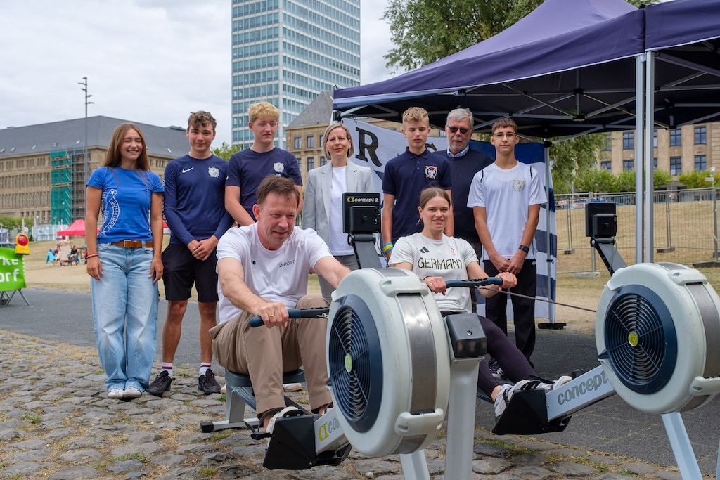 Leonie Menzel kehrte 2025 zu ihren Ursprüngen zurück, denn 2012 besuchte sie als junge Teilnehmerin das OAC am Apollo-Platz und machte erste Versuche am Ruder-Ergometer, das sie hier mit Stadtdirektor Burkhard Hintzsche testet. Mit dabei: Düsseldorfs Sportamtsleiterin Eva Kulot und Stadtsportbundpräsident Peter Schwabe © Landeshauptstadt Düsseldorf / Uwe Schaffmeister
