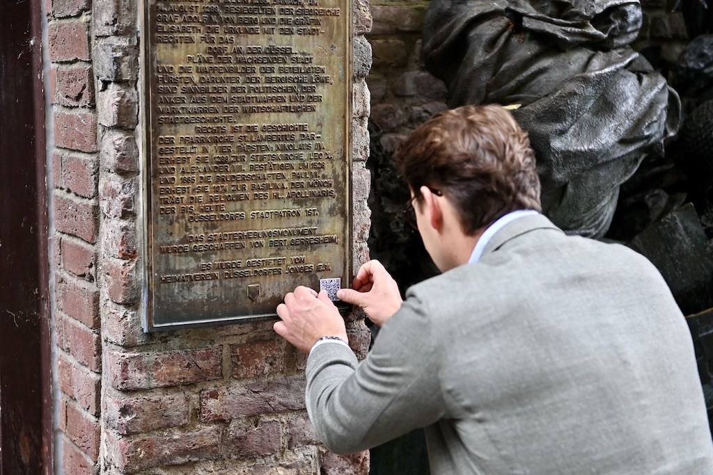Stadtbildpfleger Max Schönauer klebt den QR Code an @ Lokalbüro