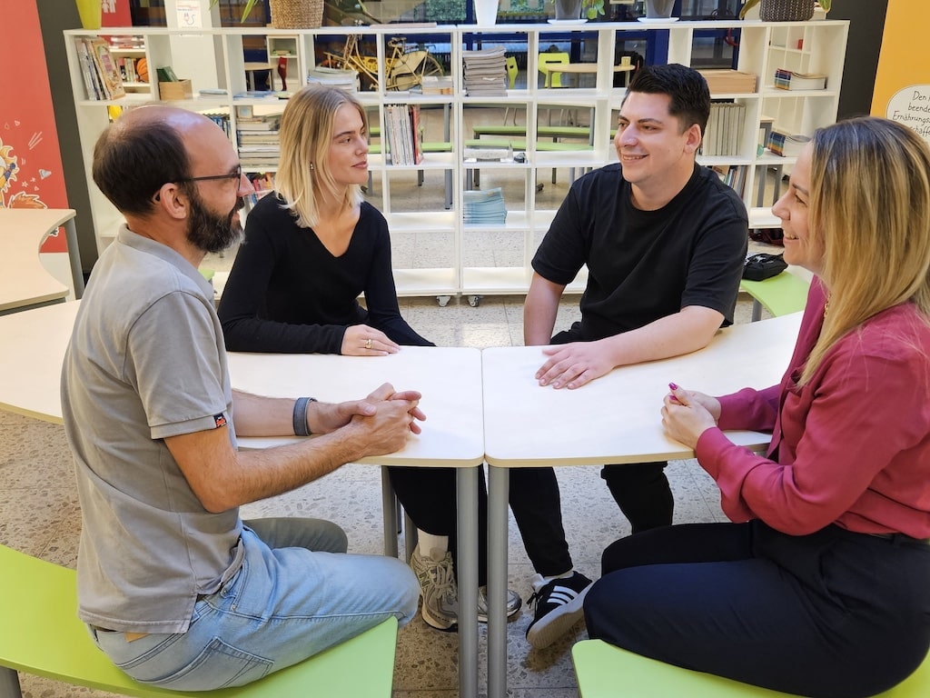 Das Familiengrundschulzentrum an der Sonnenstraße in Oberbilk nimmt an dem Projekt "Pooling" teil: Schulleiter und Projektpartner Kornelius Knettel (v.l.), Inklusionshelfende Hannah Weinert und Martin Gerblich sowie Sarah Gusovius, Abteilungsleiterin für Teilhabe und Inklusion im Amt für Soziales und Jugend, im Familiengrundschulzentrum an der Sonnenstraße. © Landeshauptstadt Düsseldorf/Amt für Soziales und Jugend