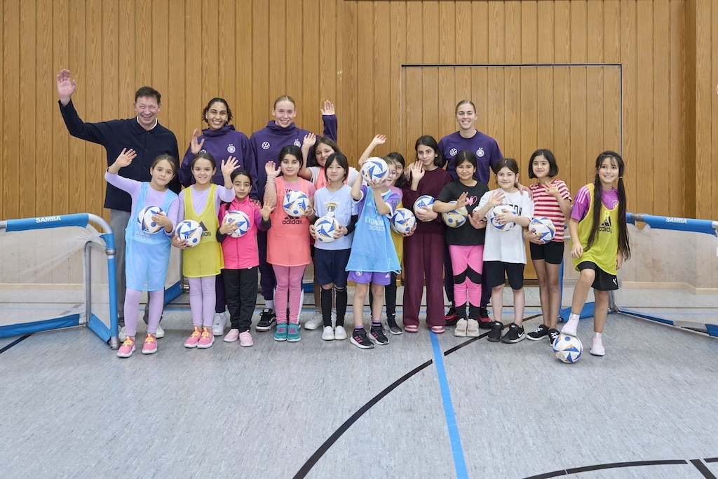 Der Besuch der deutschen Fußball-Nationalspielerinnen Laura Freigang, Cora Zicai und Laura Dick sorgte in der OGS Helmholtzstraße bei den Schülerinnen für Begeisterung. Stadtdirektor Burkhard Hintzsche ( hinten l.) begrüßte die Delegation des DFB in der OGS Helmholtzstraße. © Stadt Düsseldorf/Claus Langer