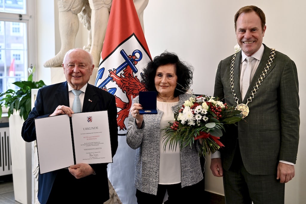 Oberbürgermeister Dr. Stephan Keller (r.) hat die Eheleute Ruth und Herbert Rubinstein am Freitag, 20. März 2026, mit der Verdienstplakette der Landeshauptstadt Düsseldorf ausgezeichnet. © Lokalbüro