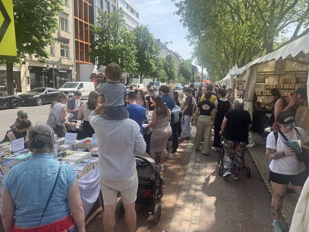 Großer Andrang auf der Kö: Hunderte Besucherinnen und Besucher flanieren bei strahlendem Sonnenschein zwischen den Büchertischen. © Lokalbüro