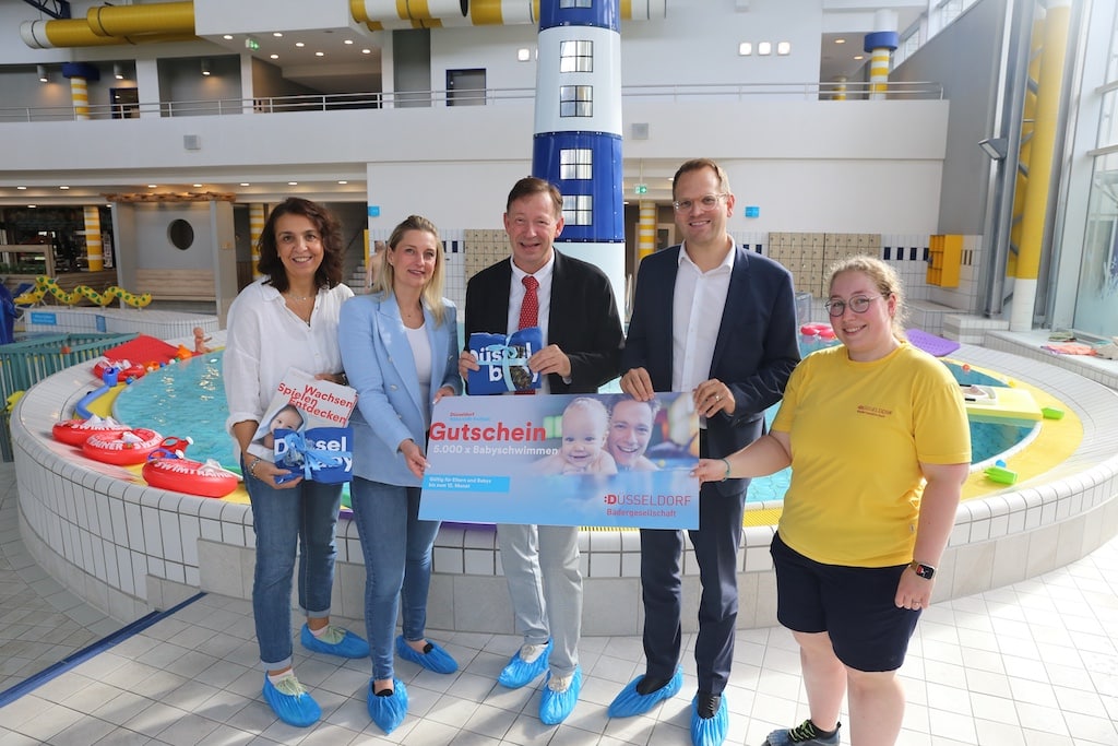 Die Bädergesellschaft Düsseldorf hat in diesem Jahr erneut 5.000 Gutscheine für das Babyschwimmen an die Landeshauptstadt Düsseldorf überreicht. Gruppenbild: (v. l.) Carima Belaouchi, Team Elternbesuchsdienst, Juliane Bruchhaus, Leiterin des Elternbesuchsdienstes, Stadtdirektor Burkhard Hintzsche, Christoph Schlupkothen, Geschäftsführer der Bädergesellschaft Düsseldorf, Julia Frühauf, leit. Schwimmmeisterin. © Landeshauptstadt Düsseldorf/Ingo Lammert