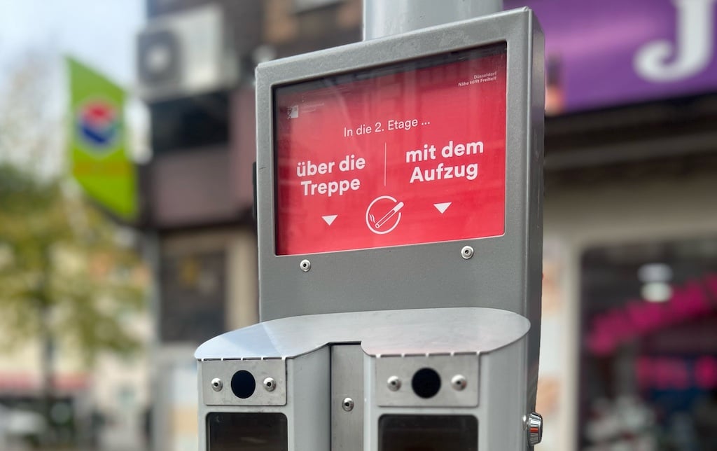 Bei der neuen Runde der Abstimm-Ascher geht es um eine Entscheidung, die sich im Alltag immer wieder stellt: "In die zweite Etage über die Treppe oder mit dem Aufzug?". Standort: Rheinbahn-Haltestelle Rath-Mitte S an der Westfalenstraße. © Landeshauptstadt Düsseldorf/Amt für Umwelt- und Verbraucherschutz